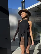 Top negro con cuello halter y diseño asimétrico de tiras colgantes en el frente.