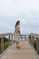 Túnica de corte amplio color beige con rayas verticales blancas, mangas 3/4 y lazo en la cintura.