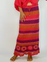 Pollera larga tejida a crochet con diseño de rayas horizontales en tonos naranja, fucsia y morado.