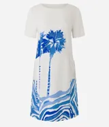 Vestido corto tipo t-shirt color crudo, con estampado de palmeras y olas en tonos azules.