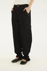 Pantalón cargo de denim negro con pespuntes en contraste, bolsillos laterales con solapa, corte relajado y terminaciones ajustables en los tobillos.