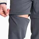 Pantalón convertible de hombre en color gris, diseñado para actividades al aire libre. Presenta un corte recto, cintura ajustable con cinturón incluido, múltiples bolsillos con cierre y tecnología repelente al agua. La prenda permite desmontar la parte inferior de las piernas para transformarse en shorts.