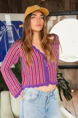 Blusa de tejido de punto calado a rayas horizontales en tonos borgoña, amarillo, lila y blanco. Tiene mangas largas que se ajustan en el codo y se ensanchan hacia el puño.