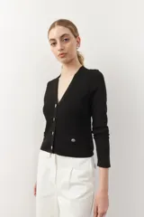 Cárdigan negro corto de tejido de punto, con escote en V, corte ajustado, cierre frontal con botones dorados texturizados y bolsillos simulados con botones dorados.