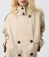 Trench coat cropped beige con capucha, cierre cruzado con botones y mangas largas.