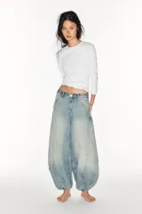 Jeans de mezclilla de tiro medio con diseño amplio tipo balloon, costuras marcadas y bajo con puño elástico. Cuenta con bolsillos delanteros y traseros, y cierre frontal con cremallera y botón metálico.