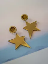 Caravanas colgantes con base redonda de resina negra rodeada de strass dorado, y dije en forma de estrella de acrílico espejado color cobre.