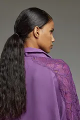 Camisa color lila confeccionada en crepe con encaje en hombros y mangas. Tiene cuello con lazo del mismo tono que se puede usar atado o suelto, escote en V, calce oversize y puños con botones personalizados a tono.
