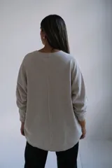 Sweater de punto color beige, de corte holgado y diseño minimalista con cuello redondo y mangas largas.