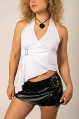 Top blanco estilo halter con escote en V cruzado y detalle de hebilla lateral drapeada, con diseño asimétrico en el dobladillo.