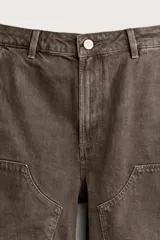 Bermuda relaxed fit color marrón con efecto lavado, cinco bolsillos, bolsillos frontales de carpintero y cierre frontal con cremallera y botón.