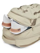 Mochila Under Armour Hustle 6.0 color beige y marrón, impermeable con tecnología UA Storm, compartimento para portátil, bolsillos laterales de malla y gran capacidad.