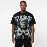Remera negra de corte oversize con estampado gráfico frontal que representa un ángel vendado sosteniendo una cruz y el texto Life Hustlers.
