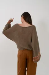 Buzo de hilo tejido a máquina color verde militar, de cuello bote y mangas anchas y cuadradas con detalle de guarda geométrica en los puños.