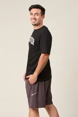 Bermuda deportiva color verde militar, de corte suelto, con cintura elástica y cordón de ajuste. Cuenta con detalles de líneas verticales en los costados y bolsillos laterales con cierre.