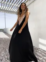 Vestido largo de fiesta color negro, con corte holgado y escote en V profundo decorado con lentejuelas doradas.