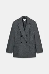 Blazer de corte oversize en color gris jaspeado, con cuello solapa, hombreras y cierre frontal cruzado con botones. Cuenta con bolsillos delanteros con solapa.