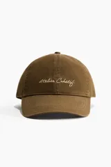 Gorra de sarga de algodón con efecto lavado en color verde militar, con bordado frontal con la frase "Atelier Créatif" en hilo claro.