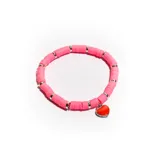 Pulsera elástica con cuentas circulares de color rosa y separadores plateados. Incluye un dije en forma de corazón rojo con borde plateado.
