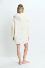 Saco de textura tipo peluche, color crema, con capucha y bolsillos frontales. Presenta un estampado sutil de corazones rojos dispersos por toda la prenda.