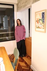 Sweater oversize de punto con diseño a rayas horizontales en color verde y blanco, cuello redondo en contraste rojo y detalle de etiqueta bordada en la manga.