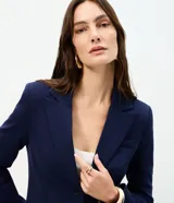 Blazer azul marino de corte entallado y largo medio, confeccionado en punto Roma con viscosa. Presenta cuello con solapa, manga larga, cierre frontal con dos botones y bolsillos con tapa.