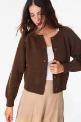 Cardigan de lana merino color crudo, de tejido de punto, manga larga y cierre frontal con botones.