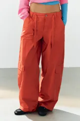 Pantalón cargo oversize de tiro medio color rojo, con bolsillos laterales y de plastrón, y lazadas ajustables en la cintura.