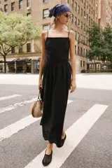 Vestido midi negro de escote recto con tirantes finos ajustables, espalda descubierta y falda amplia con bajo de bordados perforados a tono y detalle de puntilla.