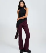 Pantalón de sastrería modelo flare en color beige, confeccionado en tejido de viscosa. Presenta un diseño de tiro alto con lazo ajustable en la cintura y detalle de friso vertical a lo largo de las piernas que estiliza la figura.