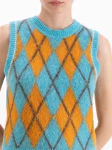 Chaleco de punto sin mangas con cuello redondo, confeccionado en hilado de baby alpaca. Presenta un diseño de rombos en colores celeste y naranja con bordes en tono oscuro.