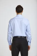 Camisa de vestir blanca de corte clásico, con cuello rígido, cierre frontal de botones y mangas largas con puños abotonados.