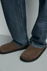 Zueco cerrado de hombre, color verde militar, fabricado en piel con acabado serraje (gamuza). Presenta plantilla acolchada y suela de goma negra con volumen.