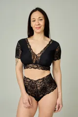 Conjunto de lencería negro compuesto por un bralette de lycra y microtul con detalles de encaje en escote, bajo busto y mangas cortas, y una bombacha hipster de tiro alto confeccionada íntegramente en encaje.