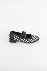 Zapato estilo Mary Jane confeccionado en cuero trenzado con diseño de damero en blanco y negro. Presenta una tira con hebilla circular en el empeine y un taco bajo cuadrado.