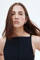 Chaleco negro entallado con escote cuadrado y breteles finos. Presenta un cierre frontal de botones y un patrón de rayas finas verticales.