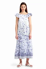 Vestido midi blanco con estampado floral azul, corte amplio, cuello redondo con volados y mangas cortas con volados.