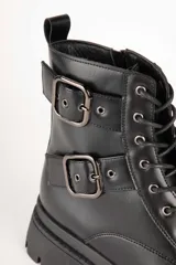 Borcegos negros de caña baja en símil cuero, con apliques de hebillas metálicas y cierre lateral. Plataforma de 5cm de alto.