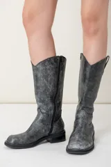 Bota de caña alta confeccionada en cuero vacuno color gris con efecto gastado. Tiene punta cuadrada, cierre en el lateral interno y suela de goma.