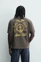 Camiseta de corte relajado con cuello redondo y manga corta. Presenta un efecto lavado y estampados a contraste en el frente y la espalda.