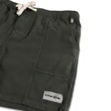 Bermuda de color verde oscuro, estilo cargo o utilitario, con cintura elástica y cordón de ajuste blanco. Presenta paneles verticales cosidos y un pequeño bolsillo cuadrado en el muslo derecho con etiqueta de marca.