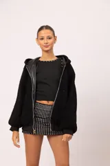 Musculosa negra entallada con cuello redondo, decorada con apliques metálicos de tachas, estrellas y ojalillos en el contorno del cuello y las sisas.