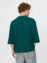 Remera de corte oversized en color beige claro, con cuello redondo y mangas de largo medio. Presenta un pequeño bordado del oso Brannan de Gap en el lado izquierdo del pecho.