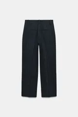Pantalón de tiro medio con pinzas delanteras y pernera recta. Cuenta con bolsillos frontales, falsos bolsillos traseros de vivo y cierre frontal con cremallera, botón interior y ganchos.