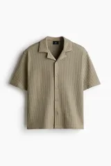 Camisa resort de manga corta color verde militar, con textura tipo waffle, cuello abierto y cierre frontal de botones.