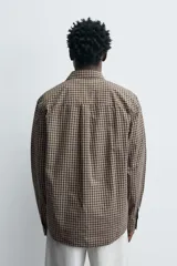 Camisa relaxed fit de algodón con estampado de cuadros en tonos marrón y beige. Cuenta con cuello solapa, manga larga con puño abotonado, bolsillo plastrón en el pecho y cierre frontal de botonadura.
