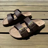 Sandalias marrones con dos tiras anchas ajustables con hebillas doradas.