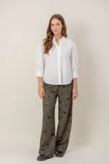 Pantalón de lana de corte recto y holgado, color marrón con textura jaspeada y apliques decorativos oscuros distribuidos por toda la prenda.