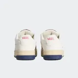 Championes Vans modelo Upland de estilo retro inspirado en los años 90. Presentan una base de ante color blanco con detalles en azul marino y rojo en el logotipo lateral en forma de V. Cuentan con una suela cupsole gruesa en tono crema, cordones anchos y cuello acolchado para mayor comodidad.