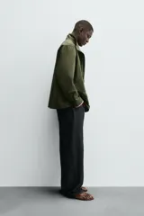 Parka de hombre color verde militar, corte regular, confeccionada en tejido técnico ligero. Presenta cuello subido, manga larga con puño ajustable y cuatro bolsillos frontales de plastrón con solapa. Cierre frontal con cremallera.